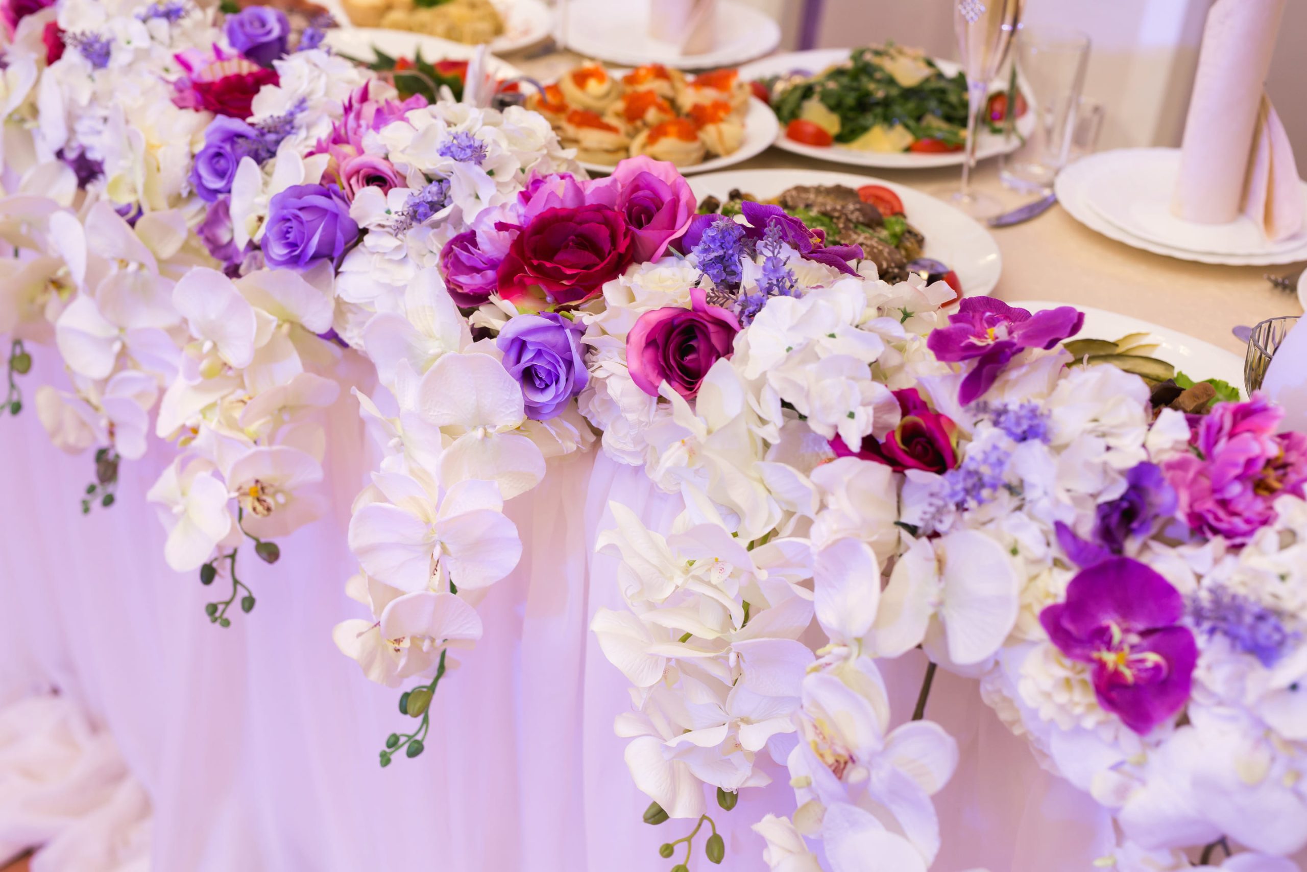 Decoración floral vibrante adornando el borde de una mesa de banquete.